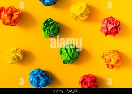 Bunte zerknitterte Papierkugel gelber Hintergrund Stockfoto