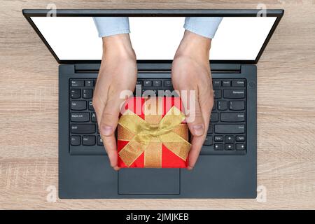 Hände mit einem Geschenk kommen von einem Bildschirm des Computers Stockfoto