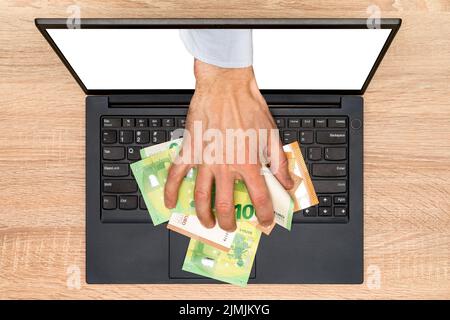 Hand greift aus dem Laptop-Bildschirm, um Geld zu stehlen Stockfoto