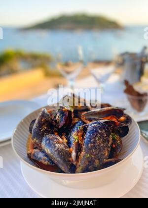 Muscheln (Mytilus) mit Tomatensauce und Knoblauch in der Abendsonne am Meer, Mallorca, Spanien Stockfoto