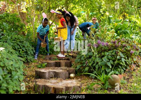 afroamerikanische Familie mit mehreren Generationen, die Ostereier in Hasenohren im Hinterhof versteckt Stockfoto