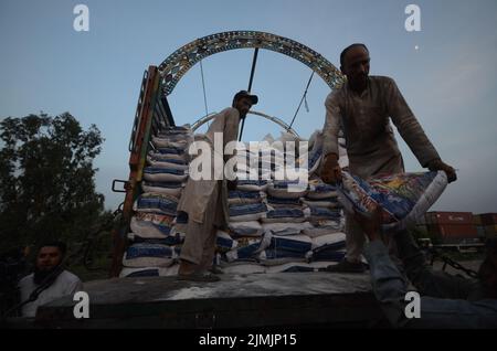 Peshawar, Khyber Pakhtunkhwa, Pakistan. 5. August 2022. Die Arbeiter laden Hilfsmaterial in einen Zug, damit die Flutopfer von der Regierung Khyber Pakhtunkhwa in Peshawar in die von Überschwemmungen betroffenen Gebiete der Provinz Balochistan geschickt werden können. Laut der National Disaster Management Authority (NDMA) sind mindestens 357 Menschen gestorben, darunter 140 Kinder, und weitere 408 wurden seit Beginn der Monsunsaison aufgrund von Regenfällen und Sturzfluten verletzt. Pakistan gehört zu den 10 Ländern, die am stärksten vom Klimawandel betroffen sind. (Bild: © Hussain Ali/Pacific Press via ZUMA Press Wire) Stockfoto