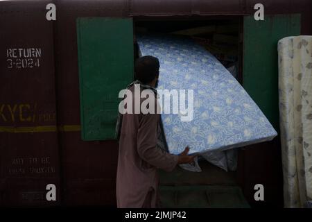 Peshawar, Khyber Pakhtunkhwa, Pakistan. 5. August 2022. Die Arbeiter laden Hilfsmaterial in einen Zug, damit die Flutopfer von der Regierung Khyber Pakhtunkhwa in Peshawar in die von Überschwemmungen betroffenen Gebiete der Provinz Balochistan geschickt werden können. Laut der National Disaster Management Authority (NDMA) sind mindestens 357 Menschen gestorben, darunter 140 Kinder, und weitere 408 wurden seit Beginn der Monsunsaison aufgrund von Regenfällen und Sturzfluten verletzt. Pakistan gehört zu den 10 Ländern, die am stärksten vom Klimawandel betroffen sind. (Bild: © Hussain Ali/Pacific Press via ZUMA Press Wire) Stockfoto