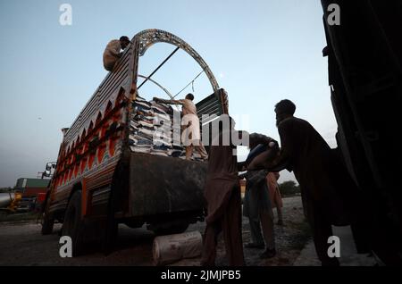 Peshawar, Khyber Pakhtunkhwa, Pakistan. 5. August 2022. Die Arbeiter laden Hilfsmaterial in einen Zug, damit die Flutopfer von der Regierung Khyber Pakhtunkhwa in Peshawar in die von Überschwemmungen betroffenen Gebiete der Provinz Balochistan geschickt werden können. Laut der National Disaster Management Authority (NDMA) sind mindestens 357 Menschen gestorben, darunter 140 Kinder, und weitere 408 wurden seit Beginn der Monsunsaison aufgrund von Regenfällen und Sturzfluten verletzt. Pakistan gehört zu den 10 Ländern, die am stärksten vom Klimawandel betroffen sind. (Bild: © Hussain Ali/Pacific Press via ZUMA Press Wire) Stockfoto