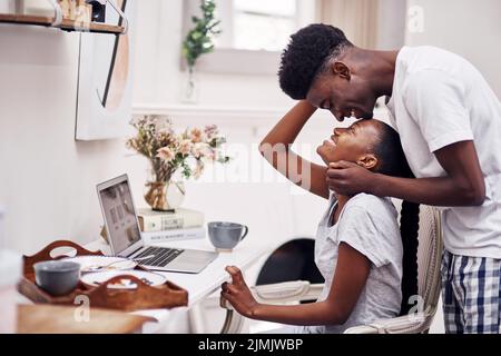 Treffen Sie mich in der Lounge, als Sie fertig sind. Ein junger Mann unterbricht seine Freundin, während er zu Hause an ihrem Laptop arbeitet. Stockfoto