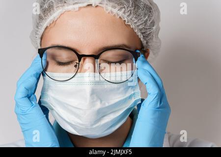 Müdigkeit - junge Ärztin mit Kopfschmerzen Stockfoto