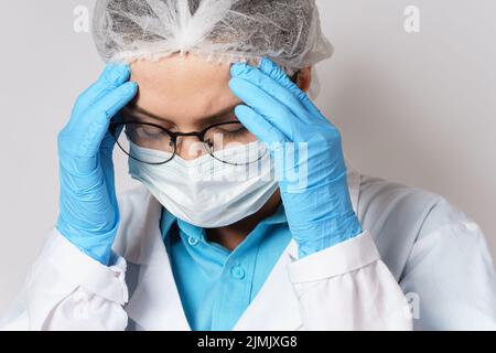 Müdigkeit - junge Ärztin mit Kopfschmerzen Stockfoto
