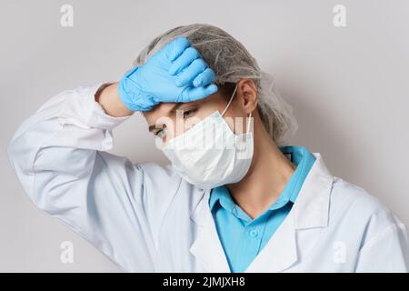 Müdigkeit - junge Ärztin mit Kopfschmerzen Stockfoto