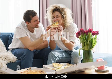 Glückliches Paar, das zu Hause leckere Pizza isst Stockfoto