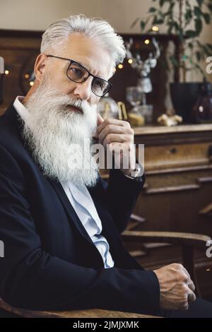 Gutaussehender bärtiger älterer Mann, der im Studio posiert Stockfoto