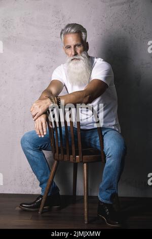 Gutaussehender bärtiger älterer Mann, der im Studio posiert Stockfoto