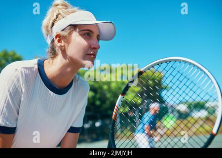 Üben Sie mit einem Zweck, spielen Sie mit einer Leidenschaft. Eine attraktive junge Tennisspielerin, die zusammen mit einem männlichen Teamkollegen draußen auf einem Platz spielt. Stockfoto