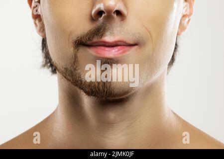 Männergesicht mit einem teilrasierten Bart. Stockfoto