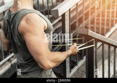 Muskulöser Mann beim Training mit einem Widerstand Gummiband auf einer Straße. Stockfoto