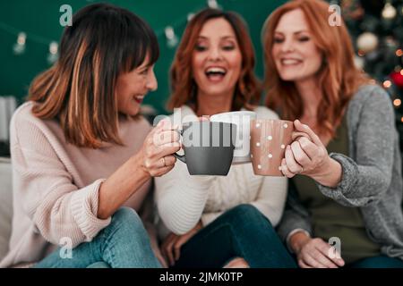 Zu einem Leben voller Erinnerungen. Drei attraktive Frauen, die zu Hause einen Kaffee auf dem Sofa trinken. Stockfoto