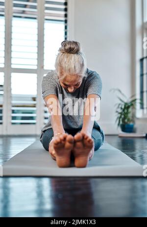 Nur noch ein wenig länger. Eine entspannte, reife Frau, die tagsüber in einem Studio Yoga praktiziert. Stockfoto