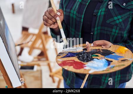 Das Leben ist Kunst, lebe dein Leben in Farbe. Eine unkenntliche Frau, die eine Malerpalette hält. Stockfoto