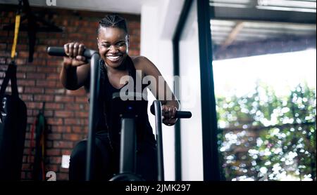 Eine attraktive junge Sportlerin, die im Fitnessstudio auf einem Crosstrainer trainieren kann. Stockfoto