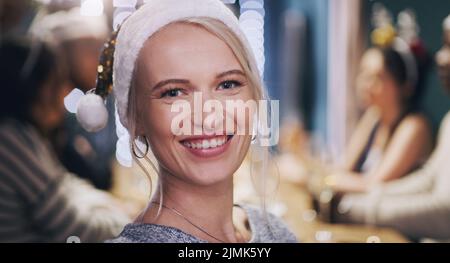 Weihnachten ist für Freunde und Familie ... und Freunde wie Familie. Porträt einer jungen Frau, die mit Freunden zu Hause eine Dinnerparty führt. Stockfoto