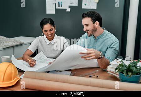 Zwei Architekten arbeiten mit Bauplänen in einem Büro. Stockfoto