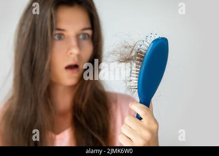 Junge Frau ist wegen Haarausfall aufgeregt Stockfoto