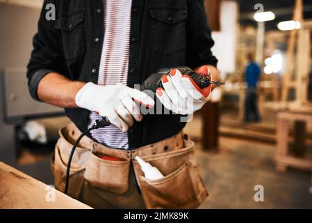 Ich bin bereit, meine Bohrmaschine anzubringen. Ein unerkennbarer Zimmermann hält eine elektrische Bohrmaschine in einer Werkstatt. Stockfoto