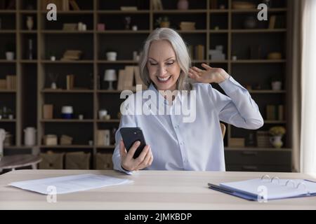 Fröhliche Rentnerin im Gespräch mit der Familie auf dem Handy Stockfoto