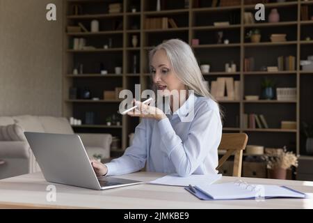 Ältere pensionierte Geschäftsfrau, die von zu Hause aus mit einem Laptop arbeitet Stockfoto