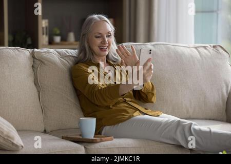 Happy Joyful ziemlich zieht Handy-Nutzer Frau winkt Hand hallo Stockfoto