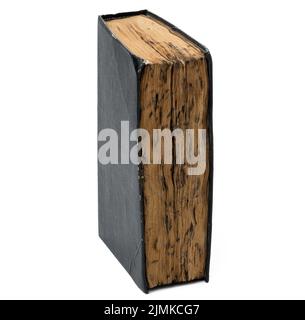 Ein sehr altes Buch mit verbrannten Laken und einem schwarzen schäbigen Einband auf einem weißen, isolierten Hintergrund Stockfoto