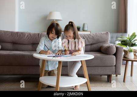 Niedliche Geschwister zeichnen Bilder in Skizzenbuch mit Bleistiften Stockfoto