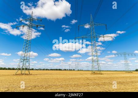 Strommasten der oberen Stromleitung unter blauem Himmel mit Wolken Stockfoto