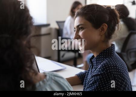 Indischer Büroangestellter hört Kollegen oder Mentoren am Arbeitsplatz zu Stockfoto