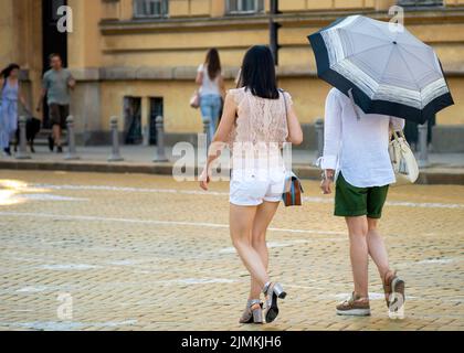 Asiatische weibliche Touristen mit Regenschirm zu Fuß auf gelben Kopfsteinpflaster gepflasterten Zar Osvoboditel Straße in der Innenstadt von Sofia, Bulgarien, Osteuropa, Balkan, Stockfoto