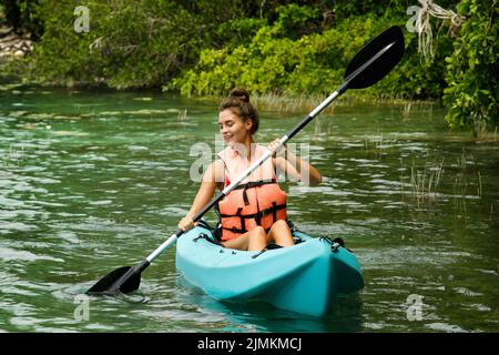 Glückliche junge Frau beim Kajakfahren auf dem See