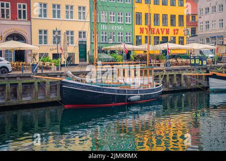Ein Segelboot steht im Hafen von Nyhavn in der Nähe der Restaurants Heering und Nyhavn 17 in Kopenhagen, Dänemark Stockfoto