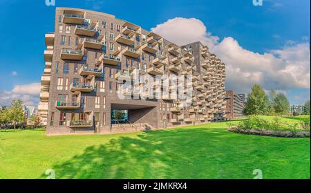 Modernes futuristisches Wohnhaus mit rechteckigen Balkonen in der Nähe eines grünen Byparken Parks im Stadtgebiet von Ã˜restad. Kopenhagen, Den Stockfoto
