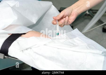 Eine Spritze in der Hand eines Arztes während einer Injektion in die Hand eines Patienten. Stockfoto