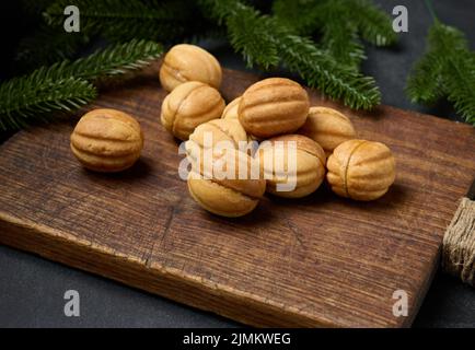 Gebackene Dessertnüsse mit Kondensmilch auf einem Holzbrett, Draufsicht Stockfoto