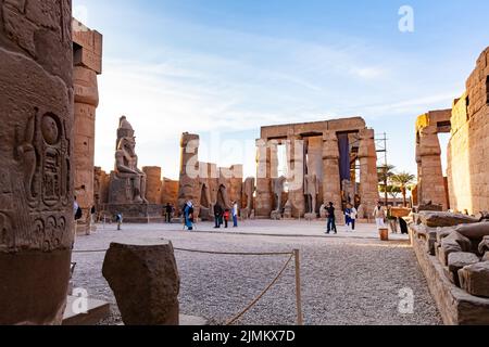 Touristen, die im Innenhof von Ramses II mit einer riesigen Statue von Ramses II. Spazieren Stockfoto