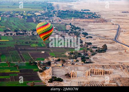 Luftaufnahme eines schönen Heißluftballons, der über den Ruinen des Tempels des Ramesseum fliegt. Stockfoto
