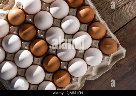 Eierhintergrund. Weiße und braune Eier in einem Papierkarton. Eiweißfutter. Öko-Bio. Minimalismus-Konzept. Stockfoto
