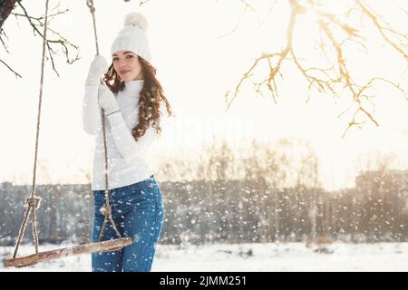 Glückliches Mädchen auf Seilschaukel an sonnigen Wintertag Stockfoto