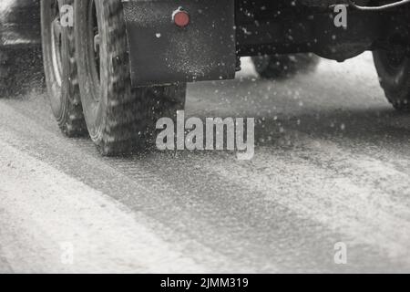 Straßen Schnee Stücke fließen von Rädern der russischen Militär-LKW bewegen sich auf Tageslicht Stadt mit selektivem Fokus Stockfoto