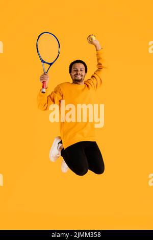 Portrait junger Mann, der mit Tennisschläger springt Stockfoto
