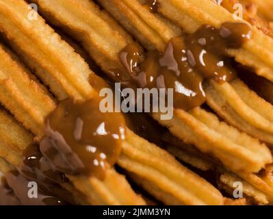 Nahaufnahme von gebratenen Churros mit geschmolzener Schokolade Stockfoto