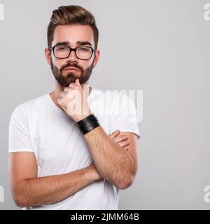 Stilvoller bärtiger Mann in Brillen vor grauem Hintergrund Stockfoto