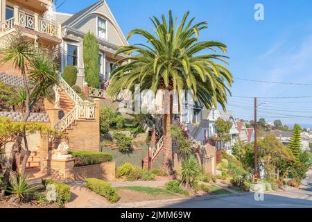 Nachbarschaft in San Francisco, Kalifornien mit Treppen und Stauen an der Vorderseite. Es gibt eine Palme und landschaftlich gestaltete Pflanzen auf der Treppenmauer in der Nähe von t Stockfoto