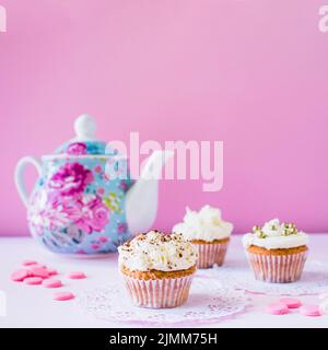 Cupcakes Bonbons Teekannen weiße Oberfläche Stockfoto