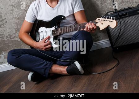 Stilvoller bärtiger Kerl mit Gitarre gegen Betonwand Stockfoto
